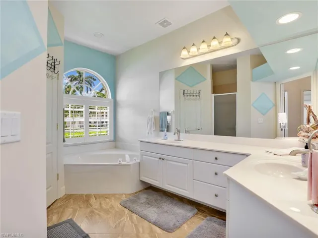 Full bathroom featuring double vanity, a stall shower, and a garden tub