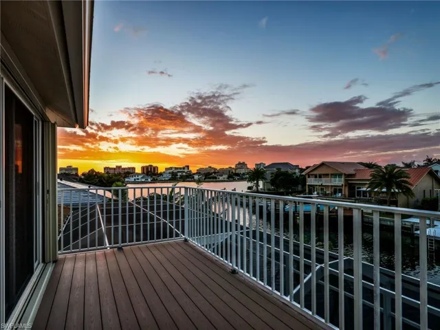 Balcony at dusk featuring a water view and a residential view