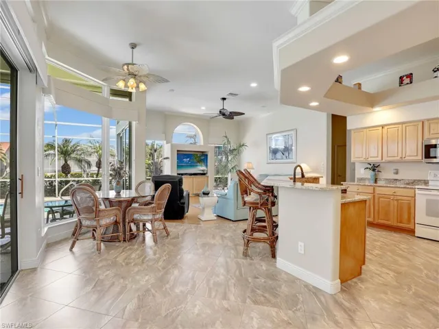 Kitchen featuring white range with electric cooktop, a ceiling fan, light stone counters, light brown cabinets, and ornamental molding