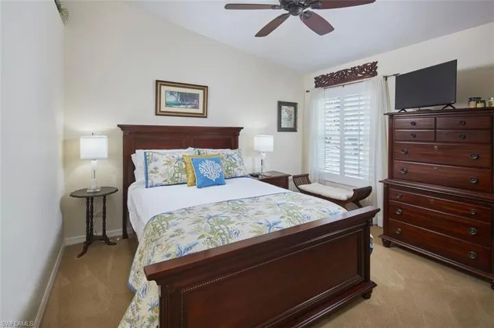 Carpeted bedroom with ceiling fan and vaulted ceiling