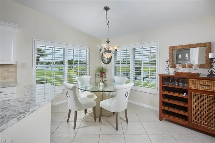 Tiled dining room with a wealth of natural light, a notable chandelier, and lofted ceiling
