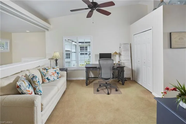 Carpeted office featuring ceiling fan and lofted ceiling