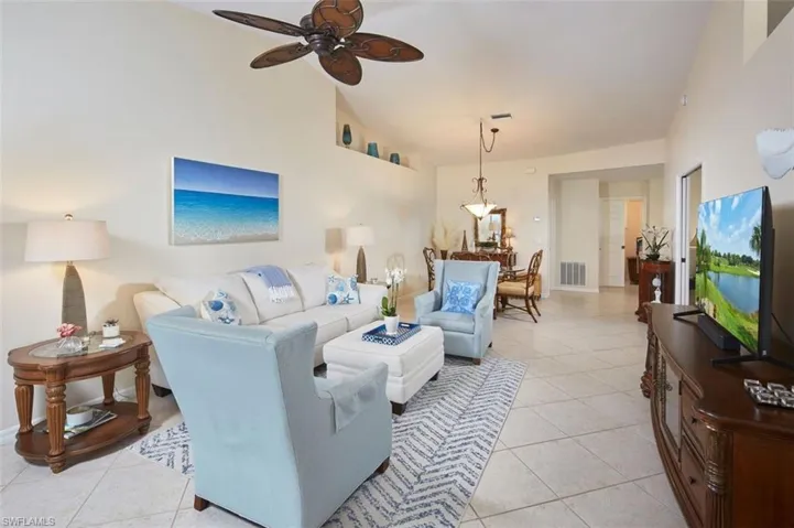 Tiled living room featuring lofted ceiling and ceiling fan