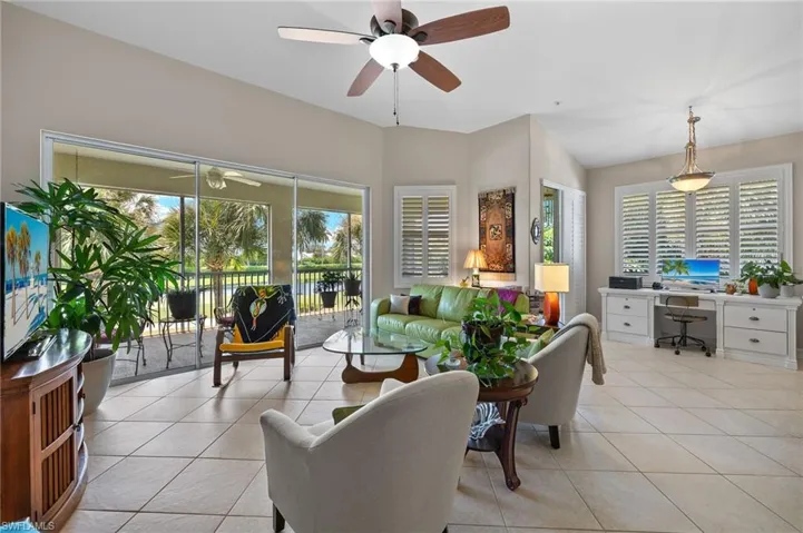 Living room with light tile patterned floors, ceiling fan, and lofted ceiling