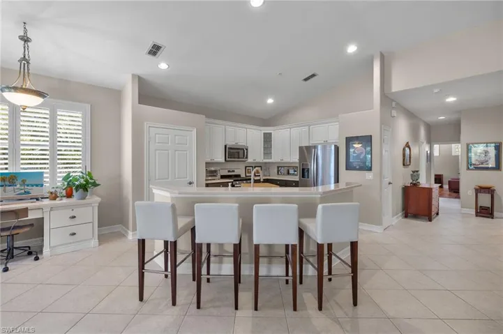 Kitchen featuring light tile patterned floors, hanging light fixtures, vaulted ceiling, white cabinetry, and stainless steel appliances