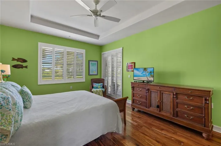 Bedroom featuring ceiling fan, hardwood / wood-style flooring, and a tray ceiling