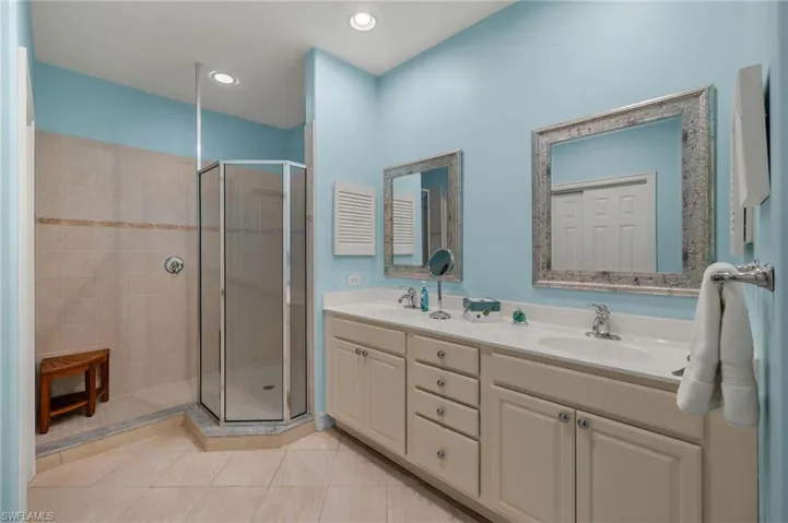Bathroom featuring double sink vanity, walk in shower, and tile patterned flooring