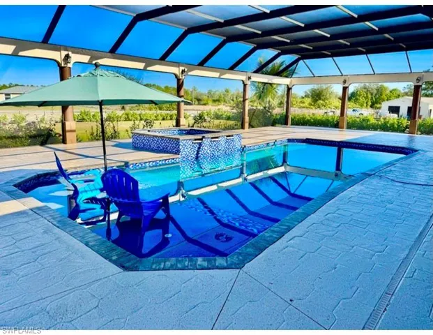 View of pool featuring an in ground hot tub, glass enclosure, and a patio area