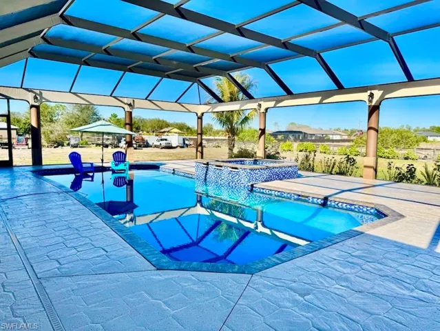 View of swimming pool with a lanai, a patio, and an in ground hot tub