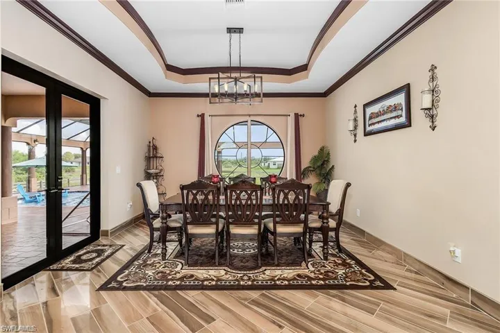 Dining area featuring a raised ceiling, plenty of natural light, a chandelier, and french doors