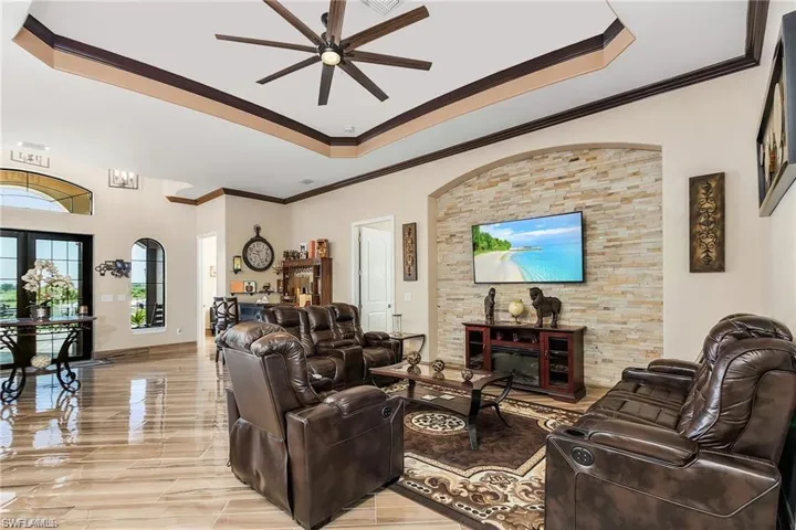 Living room featuring a raised ceiling, crown molding, and ceiling fan