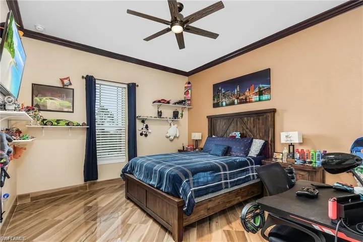 Bedroom with crown molding, ceiling fan, and light hardwood / wood-style floors