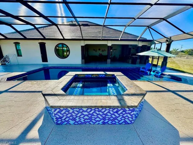 View of swimming pool featuring an in ground hot tub, glass enclosure, and a patio