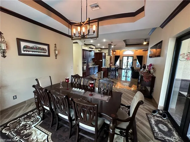 Dining area with a chandelier, ornamental molding, dark hardwood / wood-style flooring, and a raised ceiling