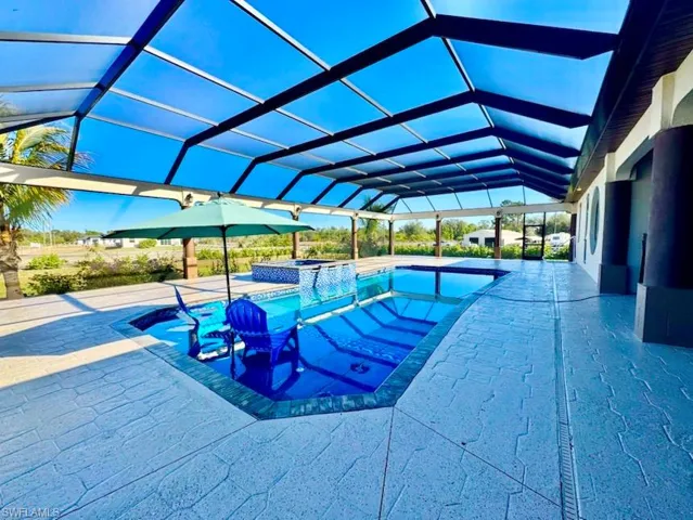 View of swimming pool with an in ground hot tub, a patio, and glass enclosure