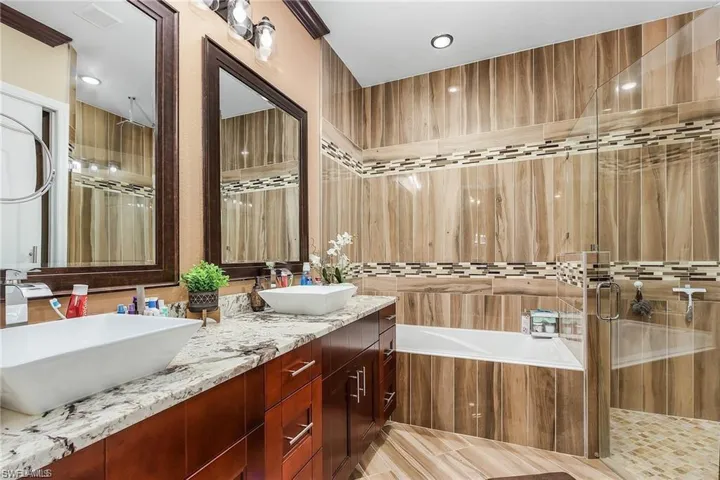 Bathroom featuring vanity, shower with separate bathtub, and tile walls