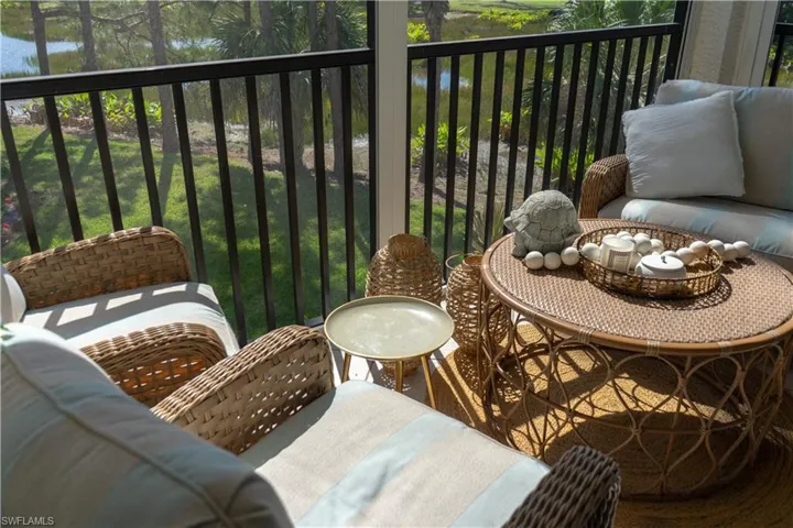 The property features an outdoor patio with a black metal railing and a view of a body of water