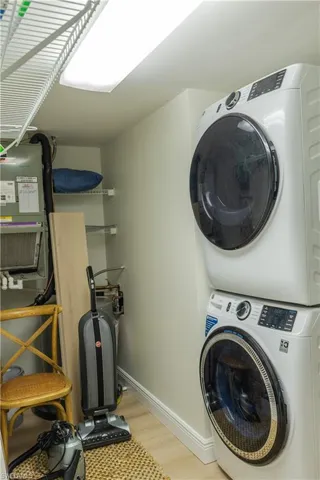 Laundry area featuring a stacked washer and dryer, light-colored walls, and a recessed ceiling light fixture