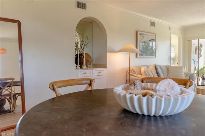 This inviting interior features a rounded table, an arched doorway, and built-in cabinetry with white drawers