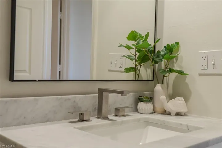 Bathroom vanity featuring a white marble countertop and a rectangular undermount sink with a modern brushed nickel faucet