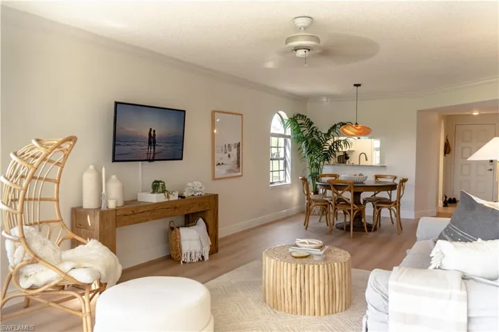 The open concept living area features light-colored walls, light wood flooring, and a ceiling fan