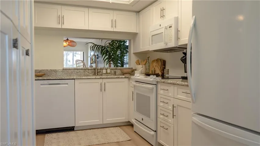 The kitchen features white cabinetry, granite countertops, and white appliances including a refrigerator, dishwasher, oven, and microwave