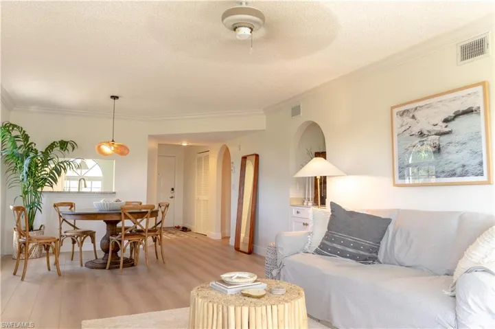 This open concept living and dining area features light-colored flooring, crown molding, and recessed lighting