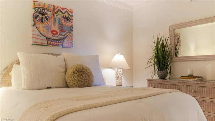 Bedroom featuring a bed with a woven headboard, a bedside lamp, and a dresser with an integrated mirror
