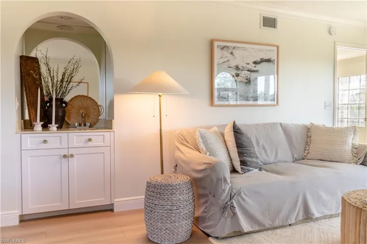 The living area features light-toned flooring, a built-in cabinet with a countertop under an arched alcove, and a contemporary framed artwork on the wall