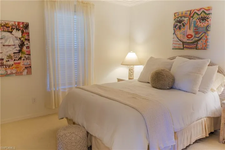 This bright room features a window with blinds and sheer curtains, and a ceiling with crown molding
