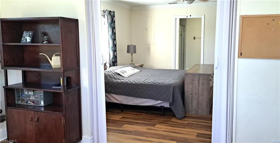 Bedroom with ceiling fan, dark hardwood / wood-style flooring, and crown molding