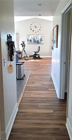 Hall with lofted ceiling and dark hardwood / wood-style floors