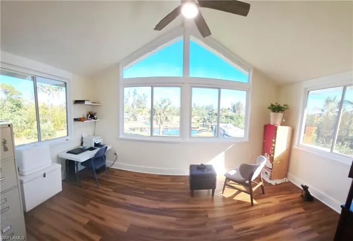Living area with ceiling fan, dark hardwood / wood-style flooring, and lofted ceiling