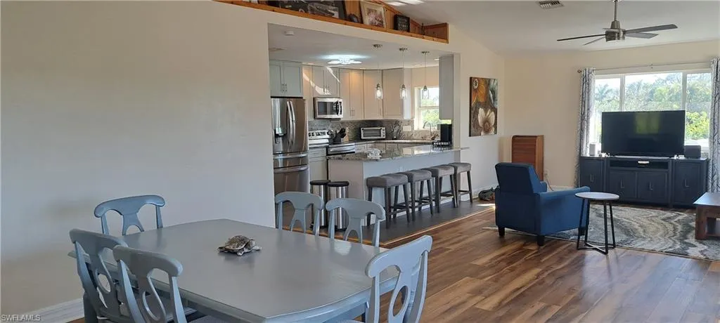 Dining room featuring ceiling fan, sink, dark wood-type flooring, and lofted ceiling