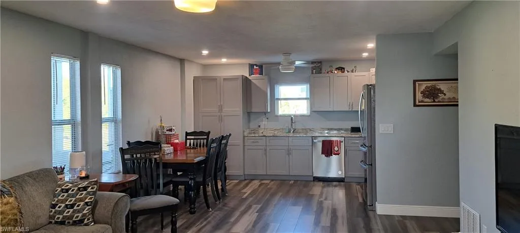 Kitchen featuring light stone countertops, ceiling fan, sink, stainless steel appliances, and dark hardwood / wood-style flooring