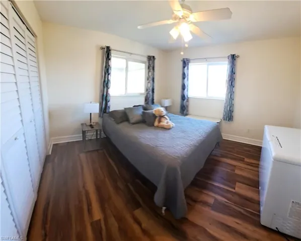 Bedroom featuring multiple windows, ceiling fan, a closet, and dark wood-type flooring