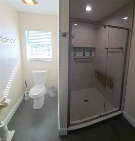 Bathroom featuring tile patterned flooring, toilet, and an enclosed shower