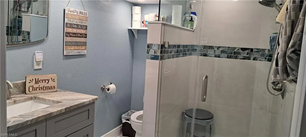 Bathroom featuring vanity, toilet, and a shower with shower door