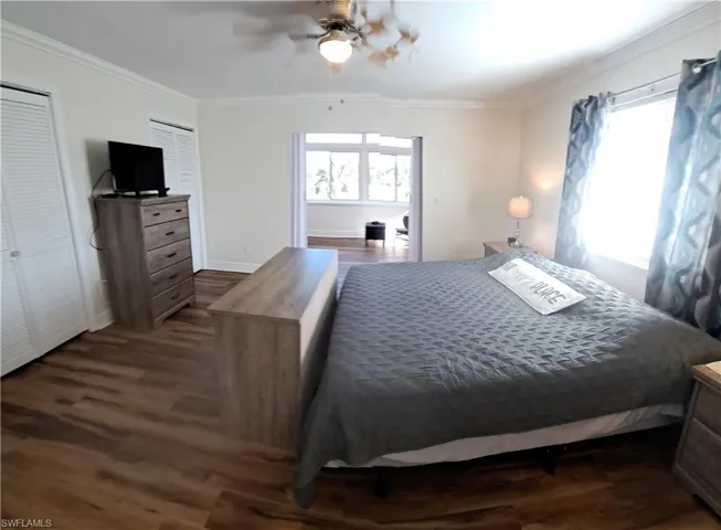 Bedroom featuring ceiling fan, crown molding, and dark wood-type flooring
