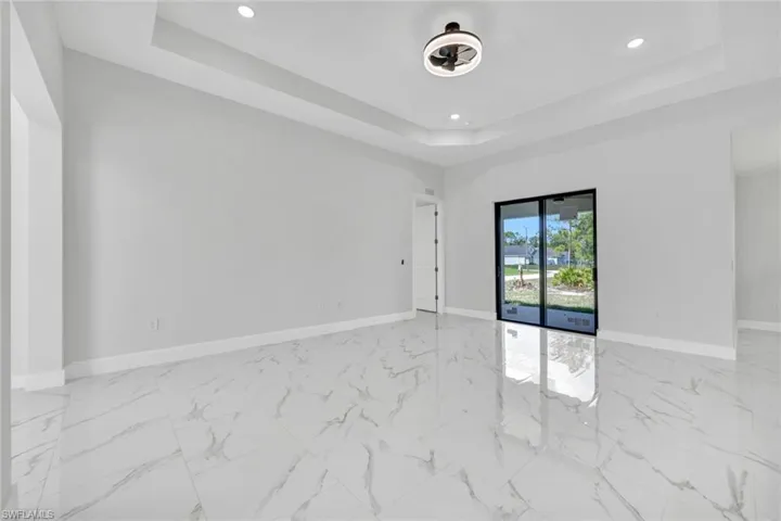 Empty room featuring recessed lighting, a raised ceiling, and baseboards