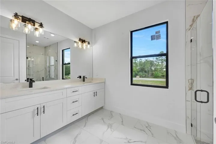 Full bath with marble finish floor, a marble finish shower, and a sink