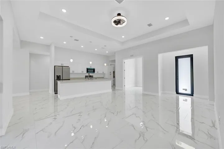 Unfurnished living room featuring a raised ceiling, visible vents, marble finish floor, and baseboards