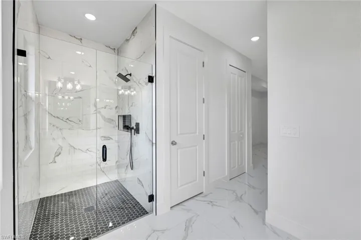 Bathroom featuring baseboards, marble finish floor, a marble finish shower, and recessed lighting