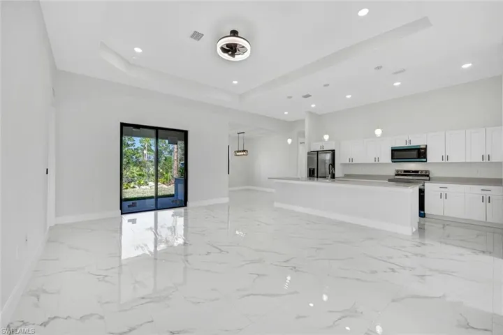 Kitchen featuring a center island, light countertops, appliances with stainless steel finishes, open floor plan, and white cabinets