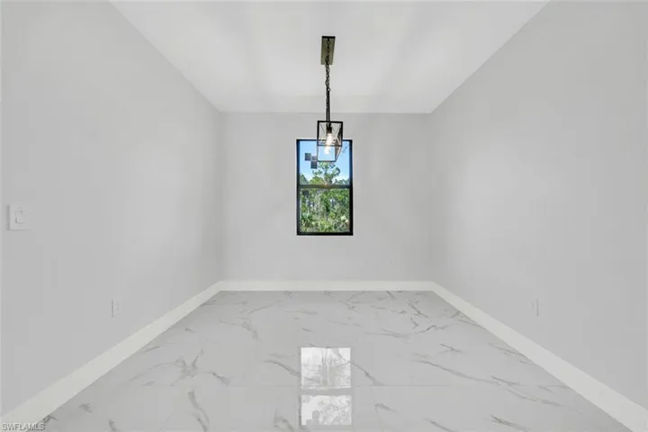 Unfurnished dining area featuring marble finish floor and baseboards