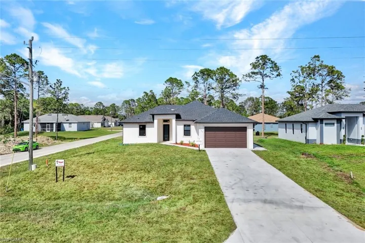 View of front of house with a garage, concrete driveway, a residential view, a front yard, and stucco siding