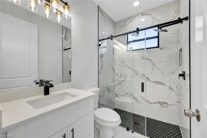 Bathroom with marble finish floor, toilet, vanity, and a marble finish shower