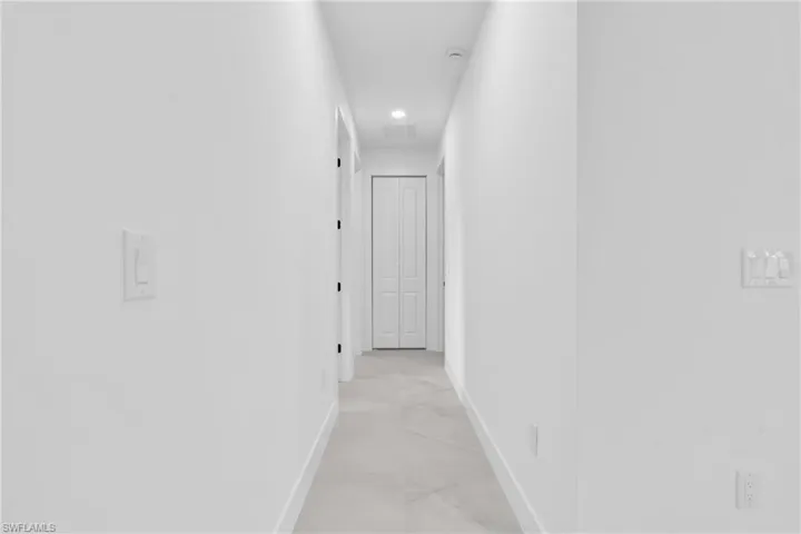 Hallway featuring light marble finish floors and recessed lighting