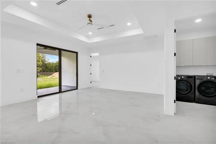 Spare room featuring washing machine and dryer, ceiling fan, light marble finish floors, a raised ceiling, and recessed lighting