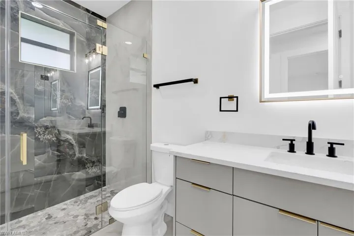 Bathroom with vanity and a marble finish shower